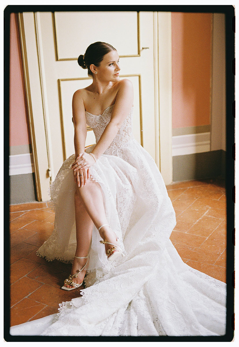 bride-villa-pozzolo-wedding-ready-sitting-on-chair-film-photography-portrait-galia-lahav-opera-07 The bride sits with legs crossed, wearing her strapless Galia Lahav Opera gown and gold-accented Jimmy Choo Zea 95 heels ready for her Villa Pozzolo wedding taken on film.