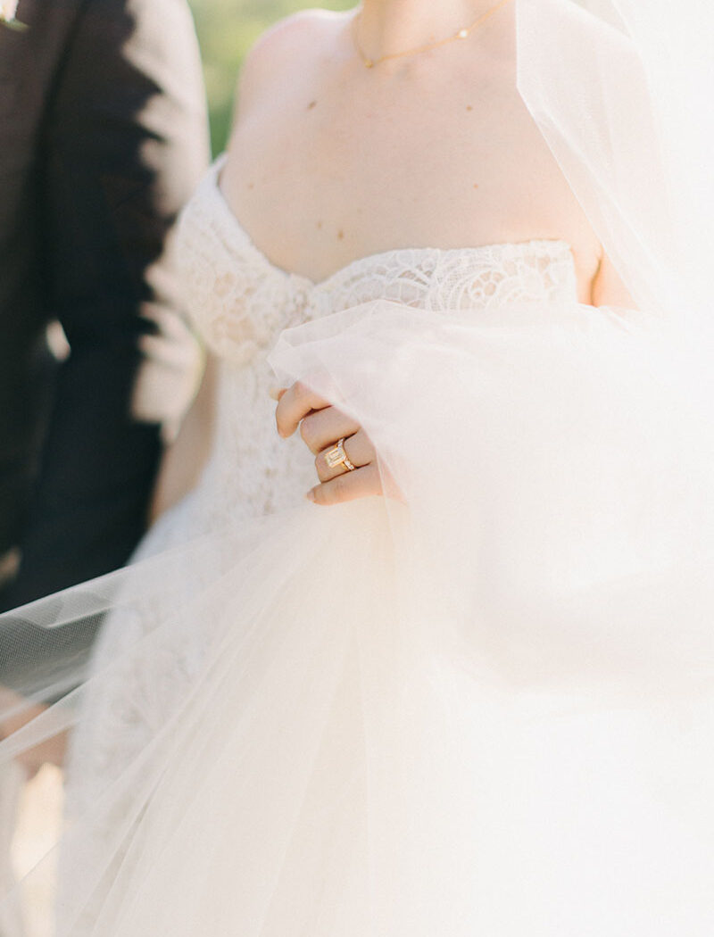 couple-portraits-villa-pozzolo-wedding-bride-details-12 Bride and groom walk hand in hand, detail shows bride holding her veil.