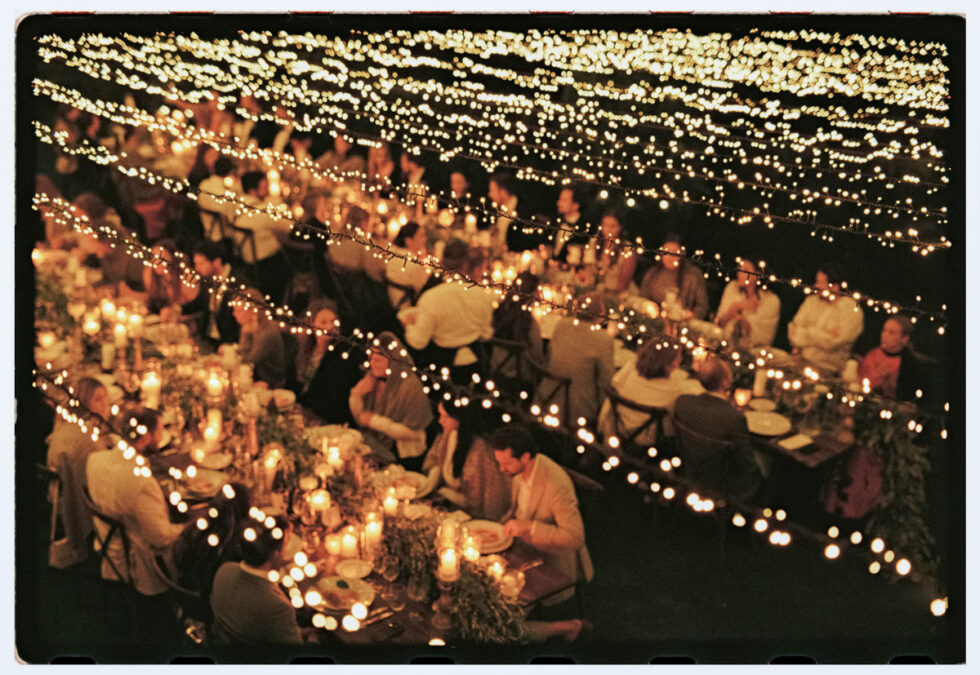 film photograph of string lights above tables during dinner