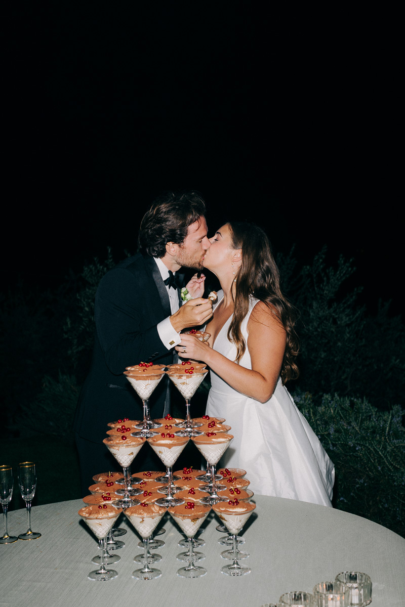 bride and groom exchange a romantic kiss in front of their tiramisu tower cake