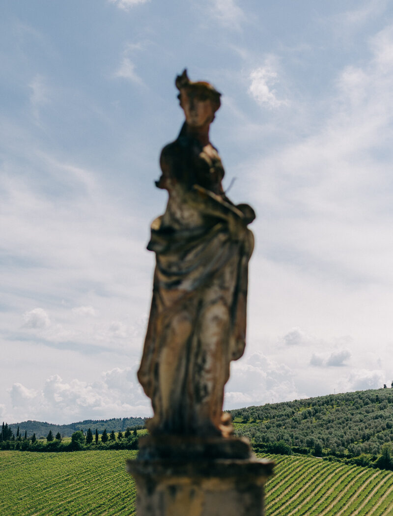 villa-corsini-wedding-8 Weathered stone statue with vineyard in the background