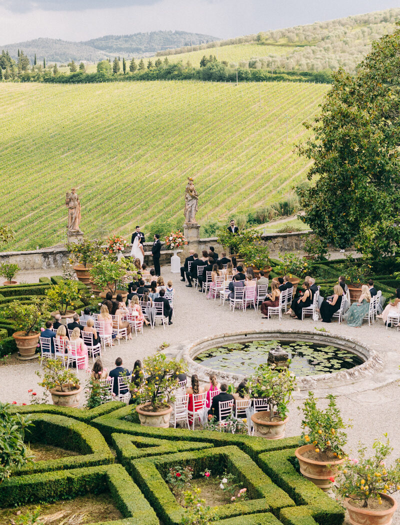villa-corsini-wedding-98 Wedding ceremony in the garden of Villa Corsini with vineyard backdrop and guests seated